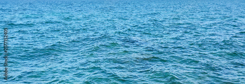 Sticker Blue sea water ripples background surface texture with gentle ocean wave movemen