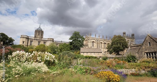 Oxford, Oxfordshire, United Kingdom, August 20, 2026. Lush flower gardens and historic gothic stone buildings under cloudy skies.