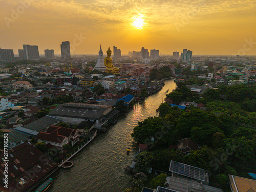 Aerial view of the Giant Golden Buddha in Wat Paknam Phasi Charoen Temple with wooden travel boat on river