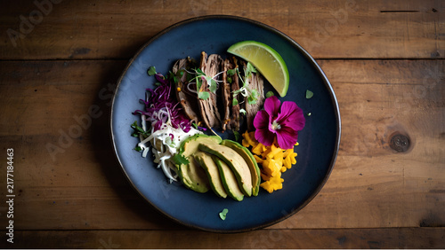 Top down view of a vibrant healthy salad bowl with avocado, meat, and edible flowers