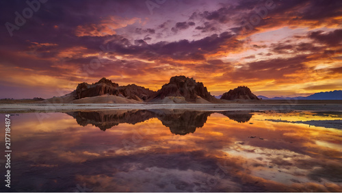 Symmetrical reflection of desert hills in a tranquil river at sunrise