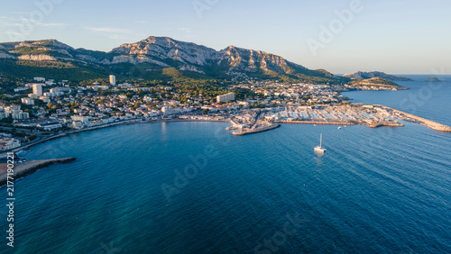 Aerial drone view of Nice, France showcasing its vibrant coastline, marina, orange‑roofed buildings, blue Mediterranean waters, and surrounding green hills under bright coastal sunlight.