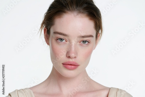 High-key studio portrait of a thoughtful woman with neutral makeup on white