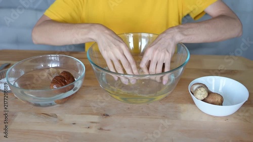 Person preparing and washing fresh porcini mushrooms in a bowl of water for cooking at home