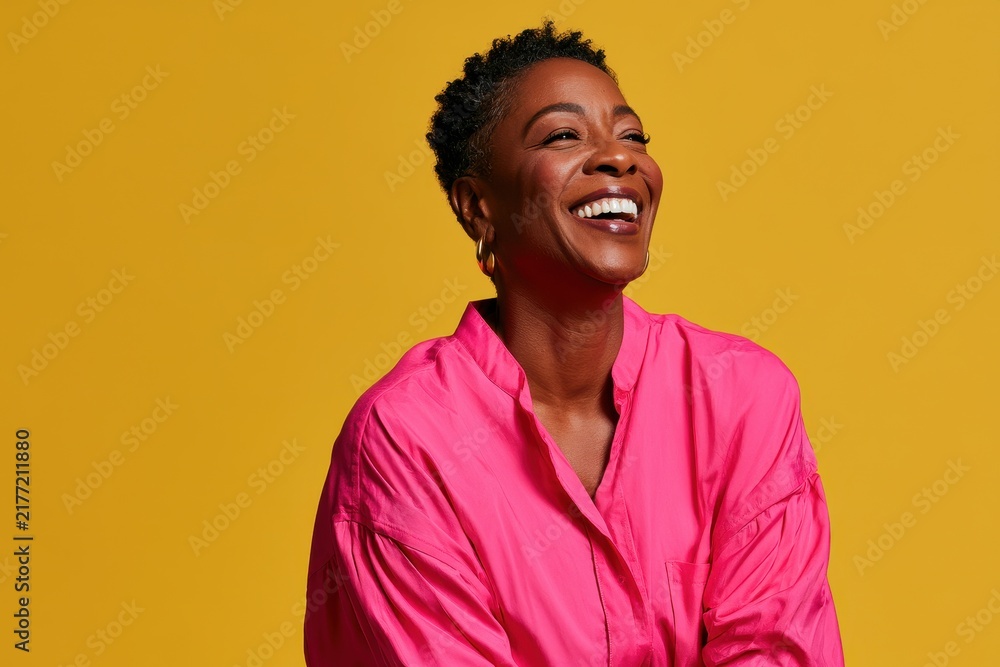 Obraz premium Optimistic studio portrait of a smiling woman in pink against a sunny yellow background