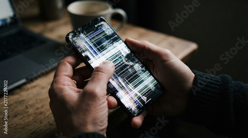 Person holding a smartphone with broken shattered screen display