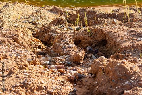 Konstfotografi Deep gullies eroded by water runoff on a sandy gravel pit surface, highlighting