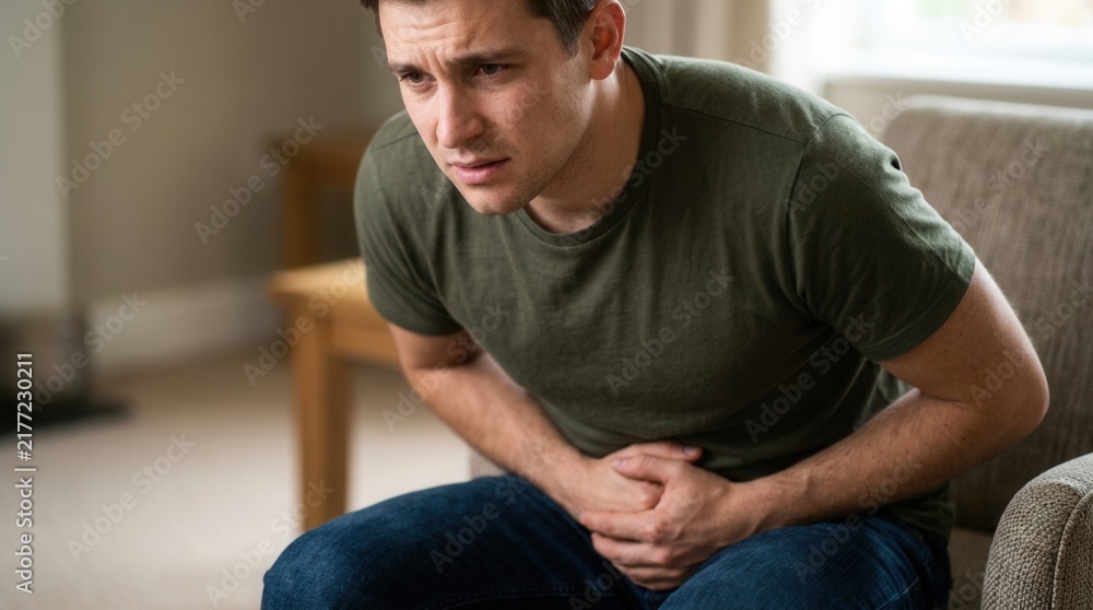 Fototapeta premium Man Experiencing Discomfort With Hands Clutched To His Stomach