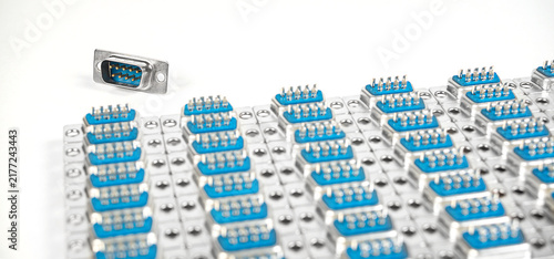 Array of blue connector pins laid out on a table with one pin placed separately from the group