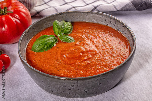 Foto Bowl of fresh gazpacho soup with basil leaves, ripe tomatoes and garlic on textu