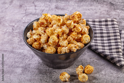 Fotografie Caramel popcorn in dark bowl with checkered cloth
