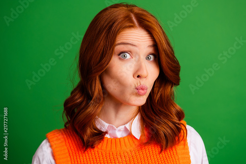 Konstfotografi Playful redhead woman puckering her lips with a surprised expression while weari