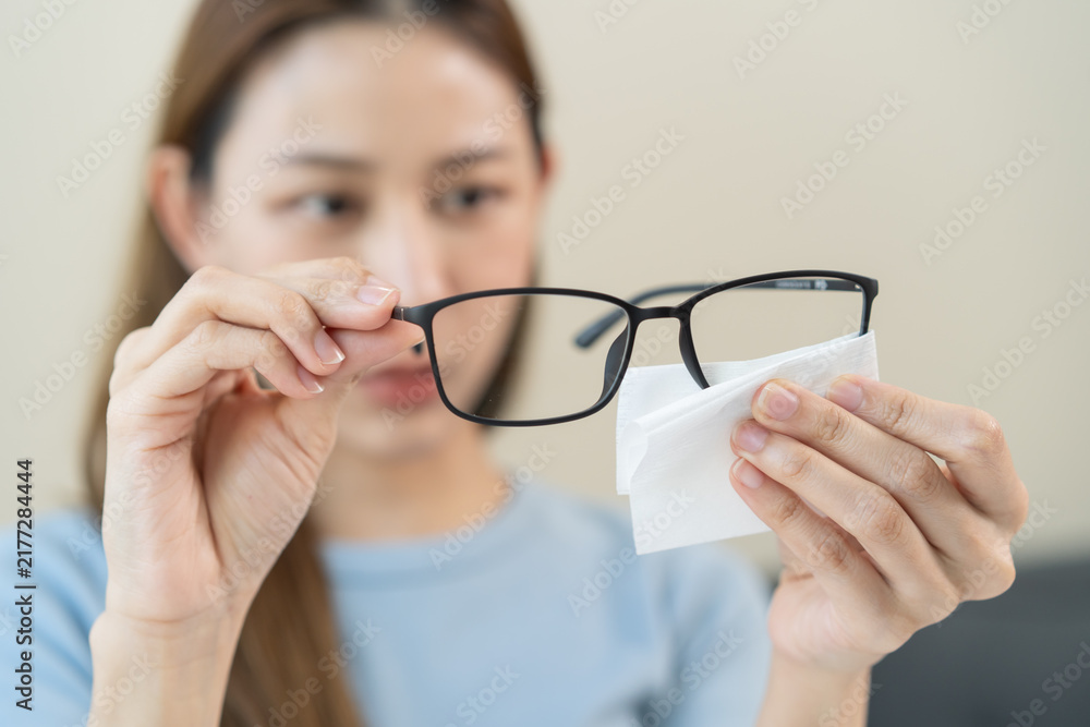 Naklejka premium Close-up person cleaning eyeglasses with microfiber fabric.