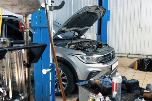 Automotive repair service, car with open hood in workshop, engine diagnostics, vehicle maintenance, garage equipment and professional mechanical service.