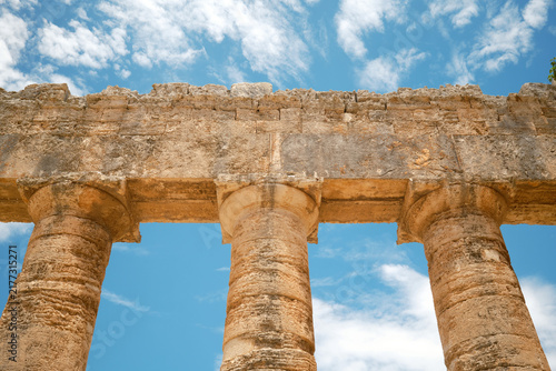 Upward view of stone architrave, entablature, and Doric capitals against blue sky in Segesta, Sicily, Italy