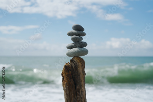 Photography Balanced stack of smooth grey stones on a weathered wooden post