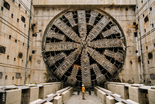 A white worker inspects a large tunnel boring machine