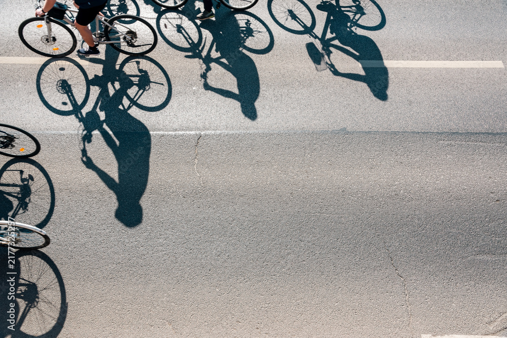 Obraz premium Aerial View of Cyclists Riding on Asphalt Street with Long Shadows
