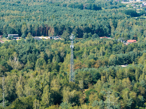 Cell tower broadcasting signal in green forest landscape, connecting modern world
