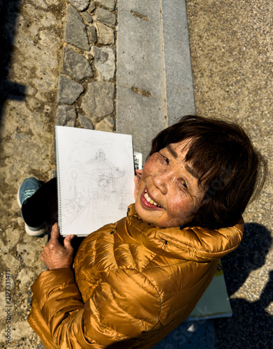 Japanese woman sketching temple drawing smiling outdoors