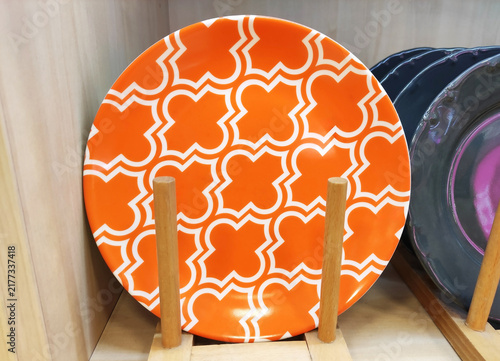 Plates with colorful decorative patterns on a wooden rack. Stylish ceramic tableware for table setting and home interior design