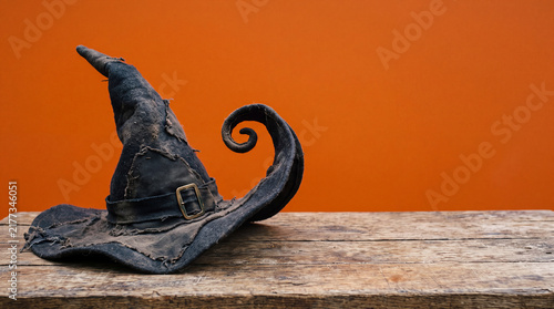 Witch Hat Floating with Curling Brim, Halloween Object on Solid Orange Background with Copy Space