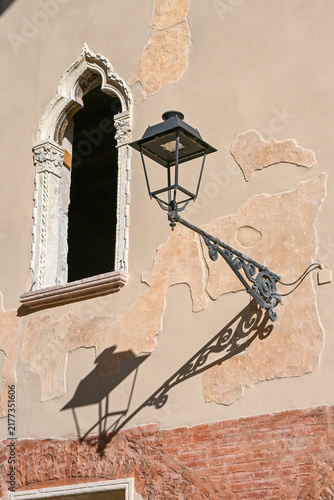 Historic arched window and ornate street lamp in Verona, Italy