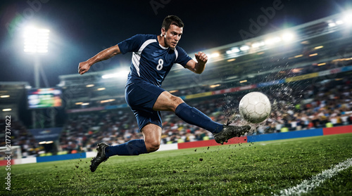 Soccer player kicking ball in packed stadium during professional football match