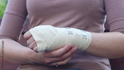 Close-up of a female hand tightly bandaged with a medical elastic bandage to fix the joint after a sprain, dislocation or fracture of the bones of the limb. Concept of first aid, treatment of injuries
