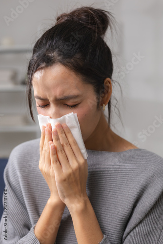 Fotografía woman sneezing into tissue while feeling sick at home, showing respiratory symptoms and illness