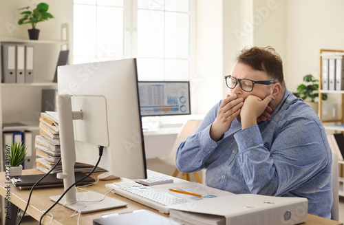 фотографія Overweight accountant in office yawns tired at computer
