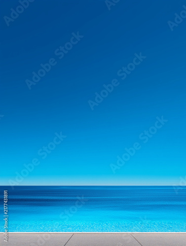 Swimming pool edge overlooking vast blue ocean