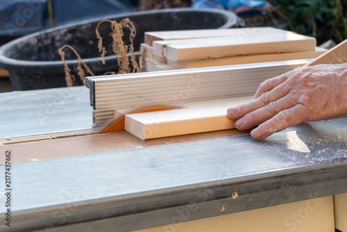 Obraz na plátne Carpenter cutting wooden board on table saw machine close up