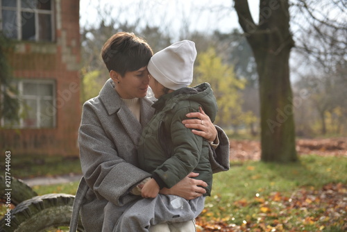 Loving mother embracing her little daughter outdoors in autumn