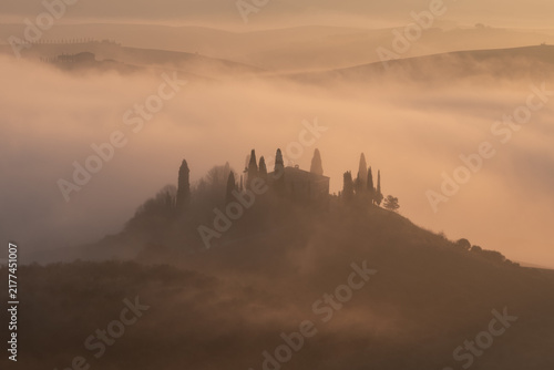 Cuadro en lienzo Aerial view of a traditional Tuscan villa surrounded by cypress trees during a misty sunrise, offering a peaceful and atmospheric rural landscape for travel and wellness