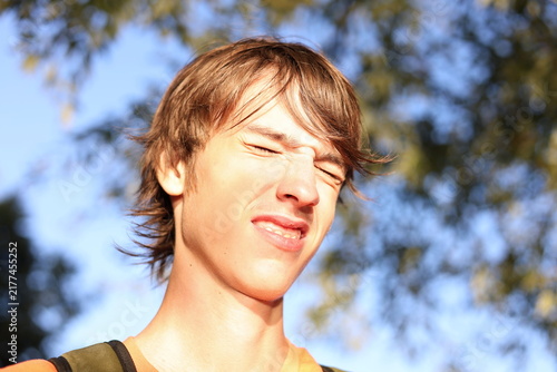 Foto Expressive teenage boy squinting and grimacing in genuine emotional reaction, co
