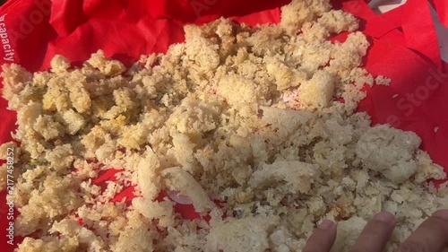 Traditional sun drying of rice grains on red fabric with hand