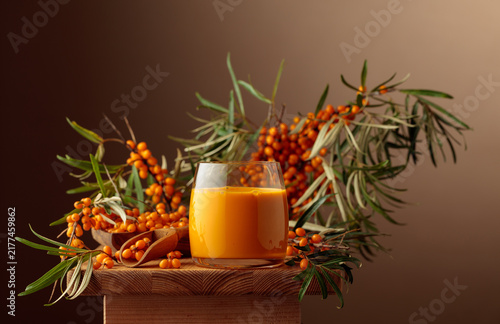 Glass of sea buckthorn juice on a wooden table.