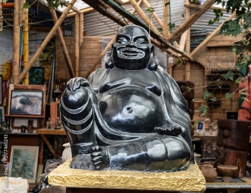 Fotografie Black laughing Buddha statue on a gold base in a workshop
