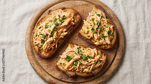 three grilled cheese sandwiches with melted cheese and herbs on a wooden cutting board, close up with warm soft lighting
