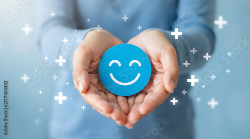 Hands Holding Blue Smiley Face Icon Representing Positivity and Wellbeing.