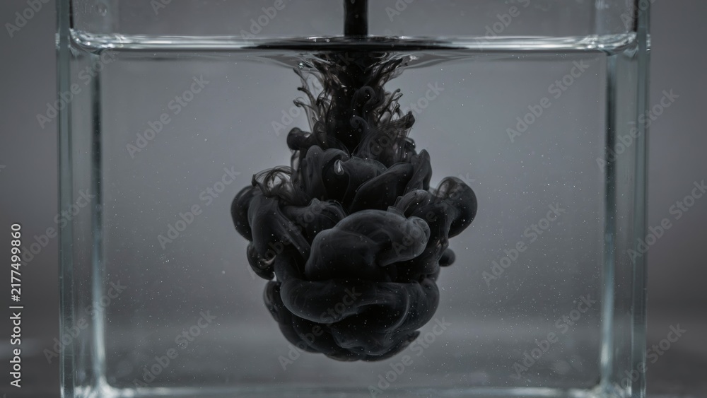 Obraz premium Black ink dispersing into clear water creating a unique organic shape inside glass container.