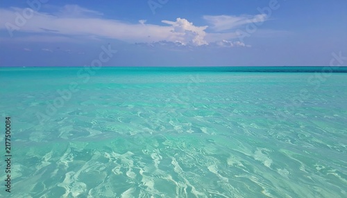 Crystal clear turquoise water of the tropical ocean under a bright blue sky.