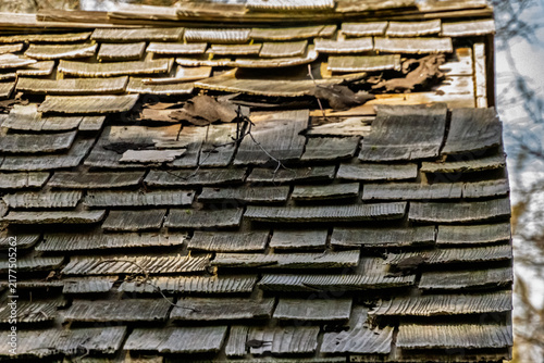 Close-up of an aged wooden shingle roof showing severe weathering, decay, damage, and natural deterioration