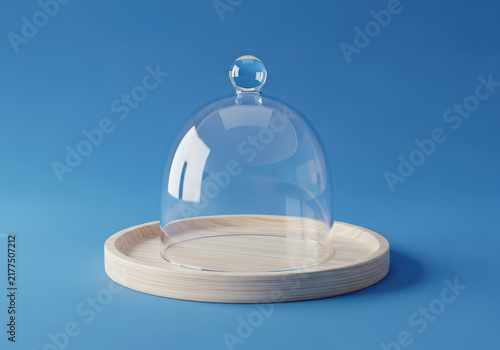 Clear glass food dome with a light wooden tray on a solid blue surface