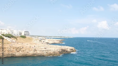 People Walking on Rocky Cliffs Above Deep Blue Adriatic Sea in Polignano a Mare Italy