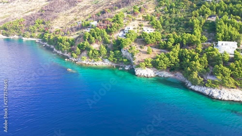 Drone view of an Adriatic coastal town with turquoise sea, green hills and a beach.