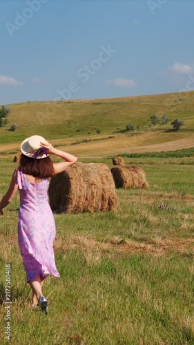 Woman in Dress Walking Through Hayfield in Rural field with hay bales