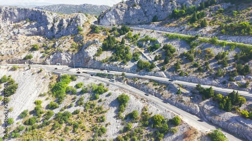 Aerial drone view of a winding serpentine road crossing a rugged limestone mountain landscape near Brela and Makarska in Dalmatia, Croatia.