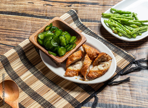 Fotografie Deep fried meat rolls with cucumber salad on a wooden table, traditional Asian appetizer